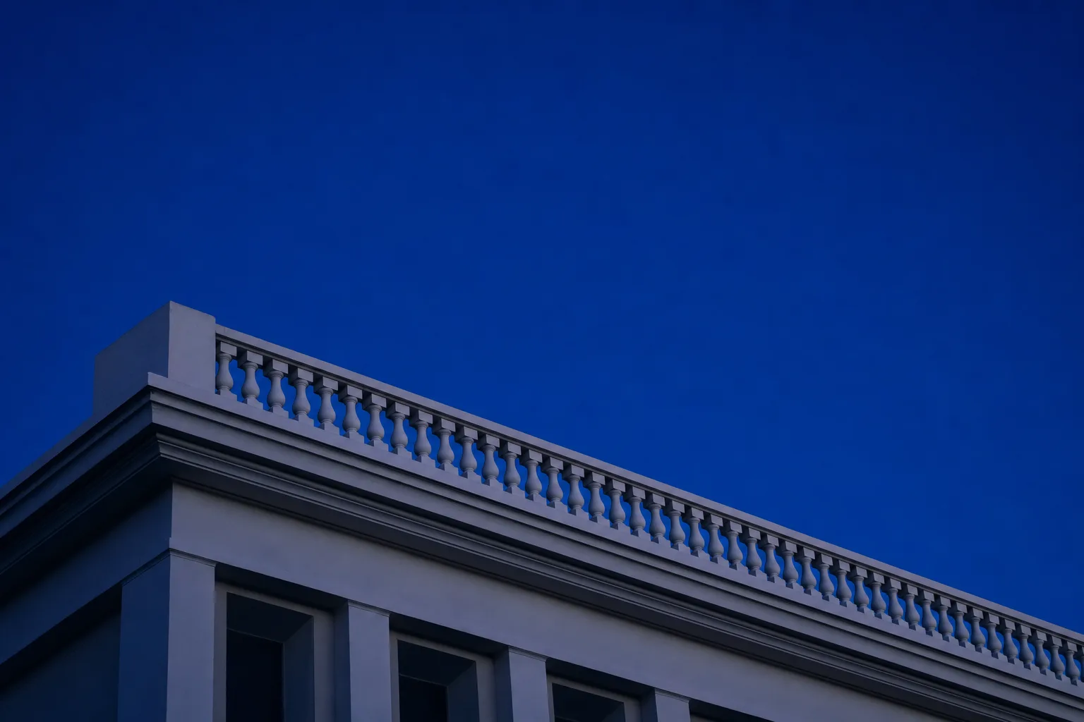 Cornisa y balaustrada de un edificio contra el cielo de hora azul