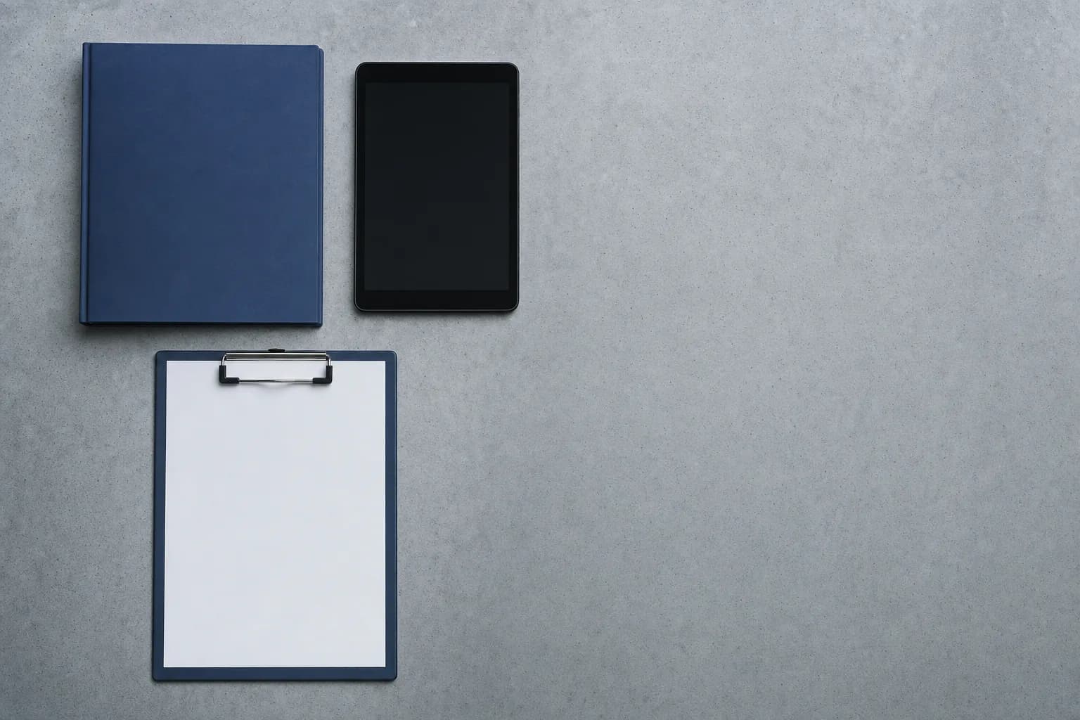 Carpeta azul, tableta y tabla con papel en blanco sobre una mesa de hormigón