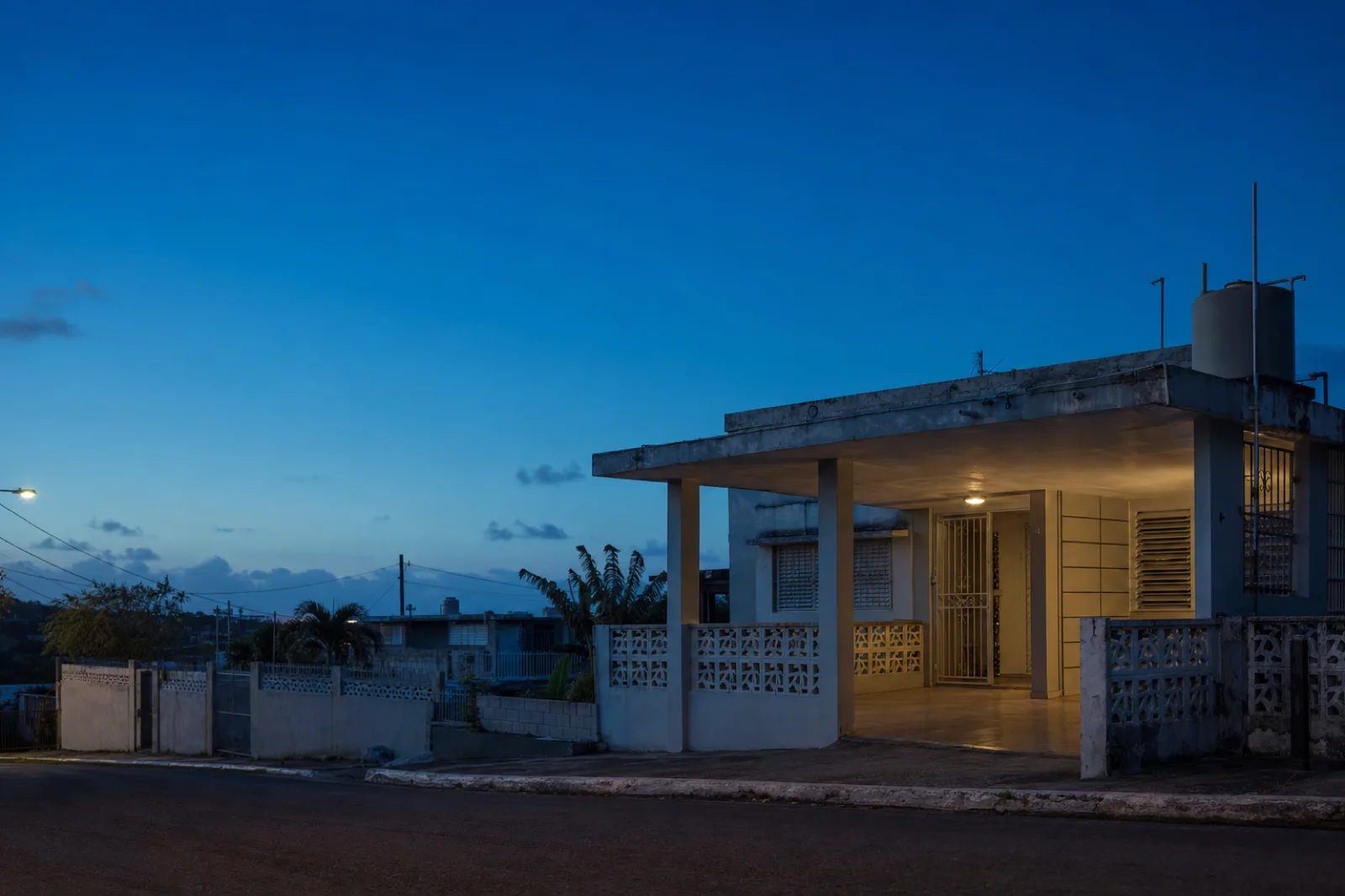 Casa puertorriqueña al caer la noche con la marquesina encendida